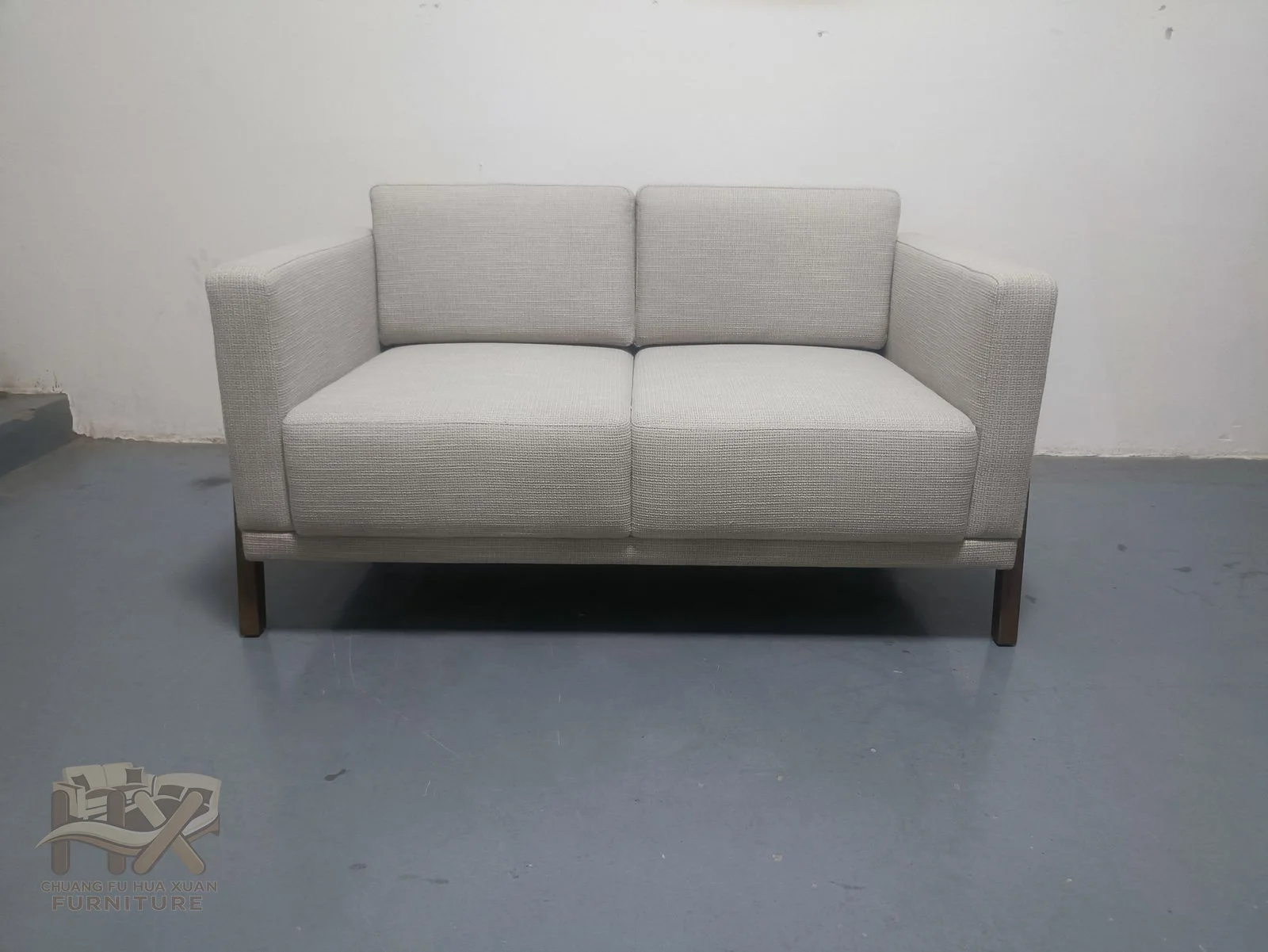 An ivory sofa and companion armchair share low square arms and loose pale cushions.
