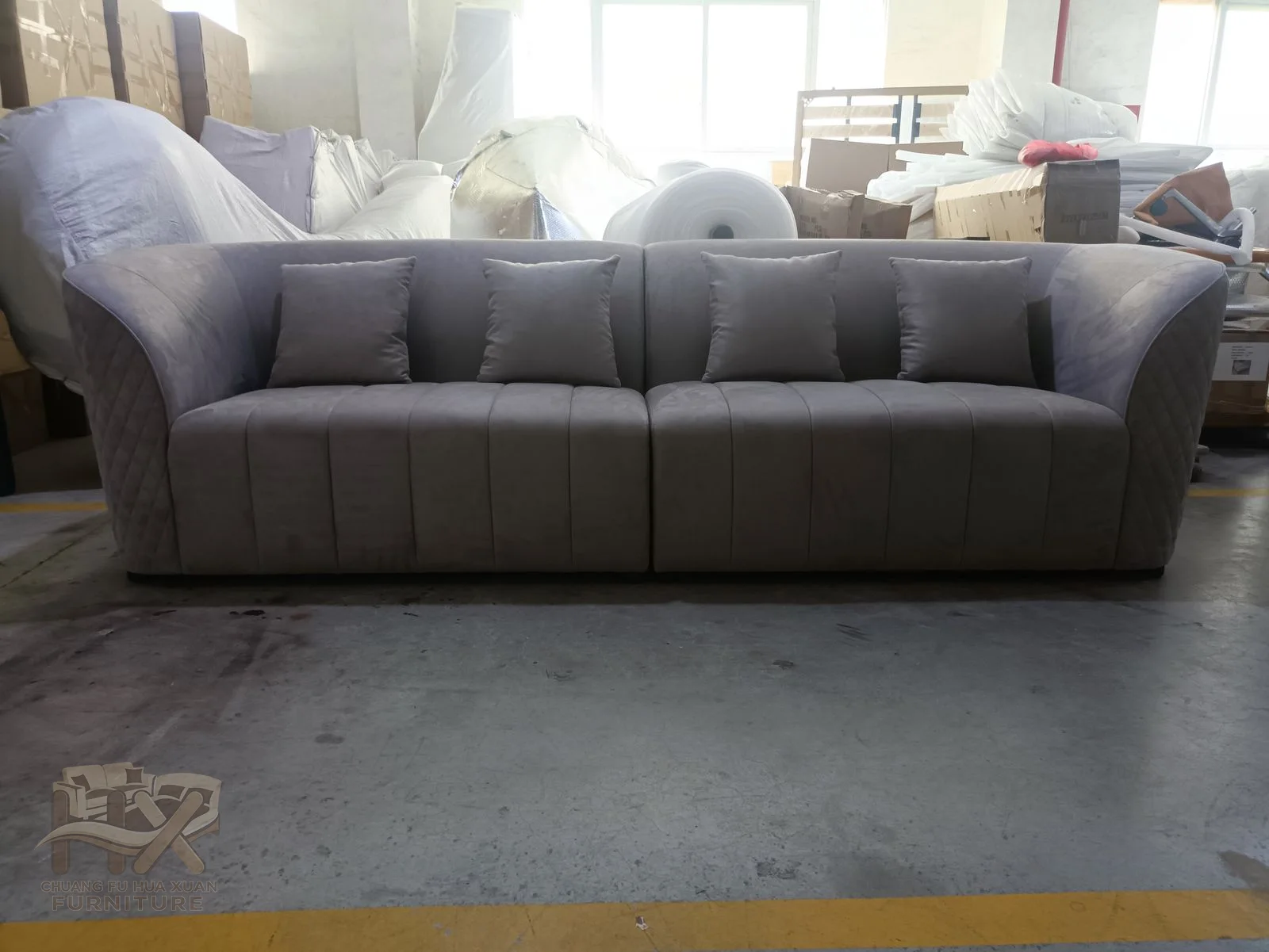A grey sofa rounds its substantial arms around a low back and deep cushion run.