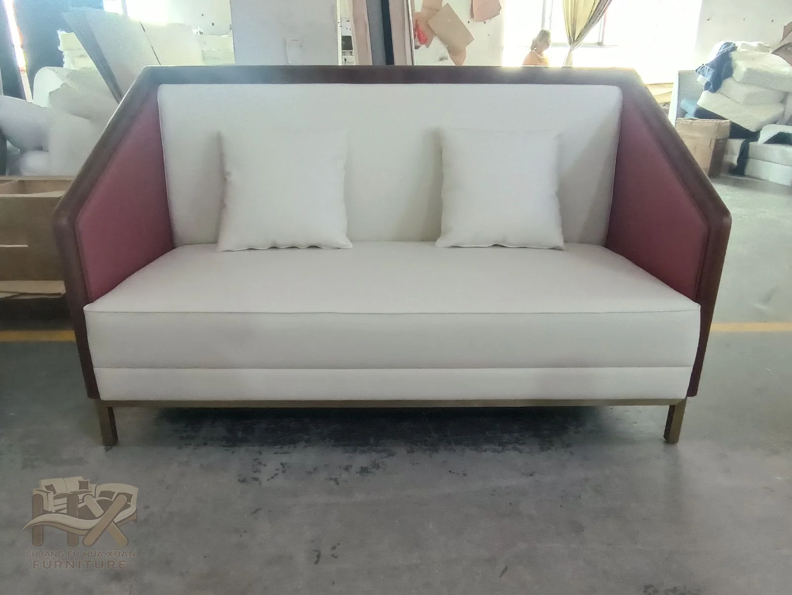 A pale sofa has burgundy outer arm panels around a straight white seat and back.