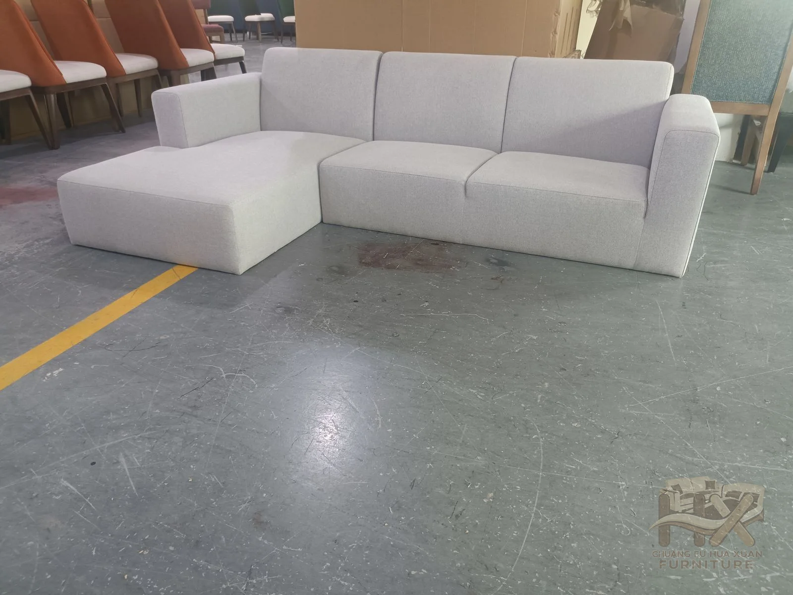A pale sofa extends into a corner chaise beside a straight cushion run and low arms.
