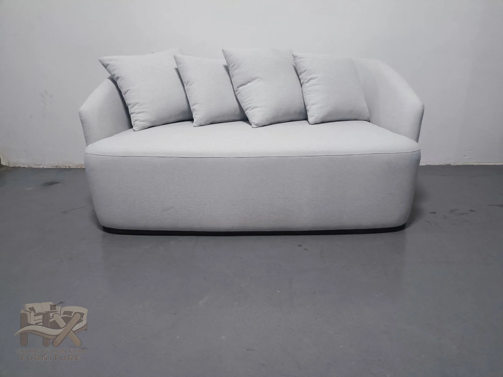 A white rounded sofa has a low curved back enclosing a broad cushioned seat.