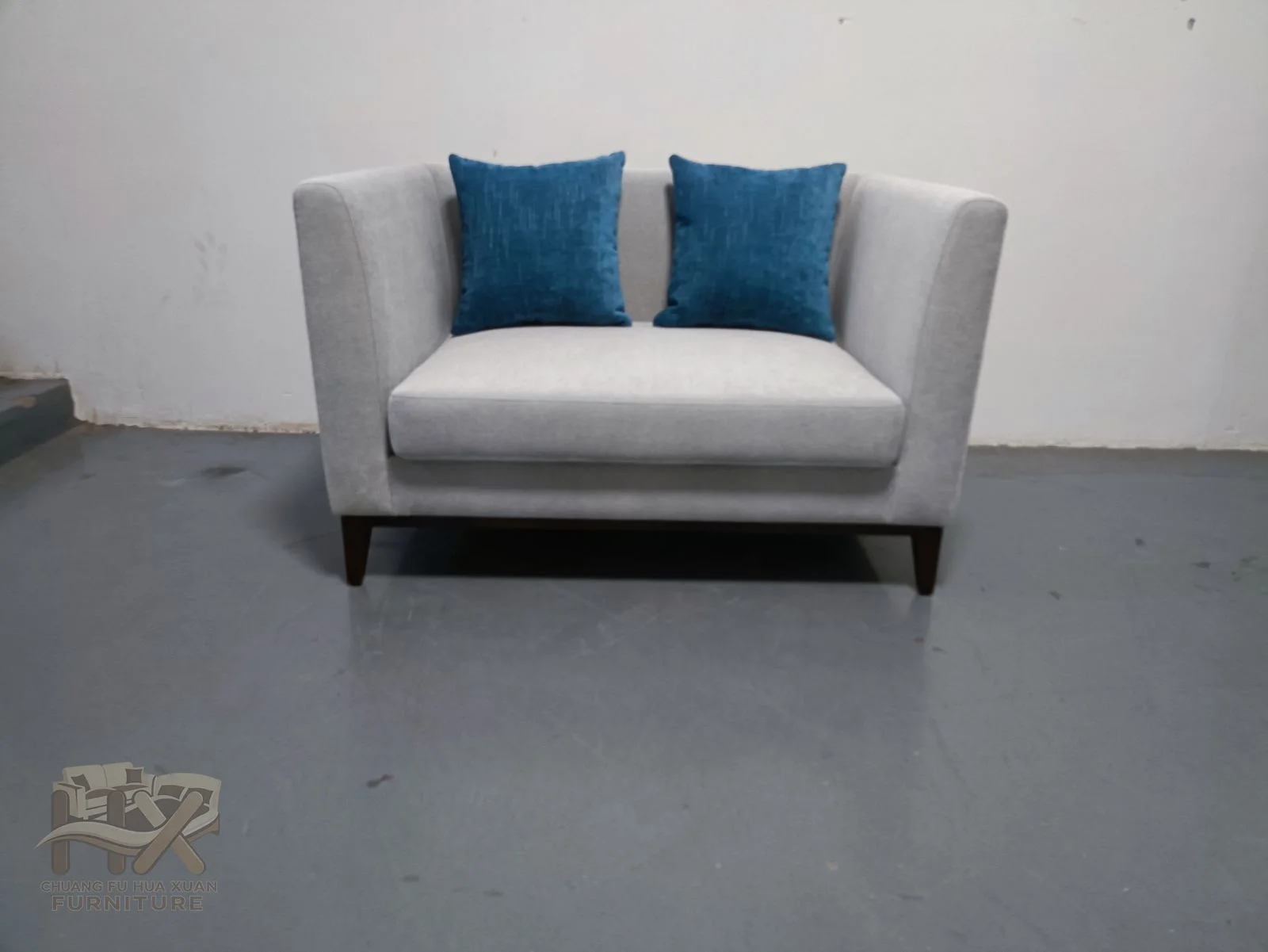 A white square-arm sofa holds contrasting blue loose cushions along a broad seat.