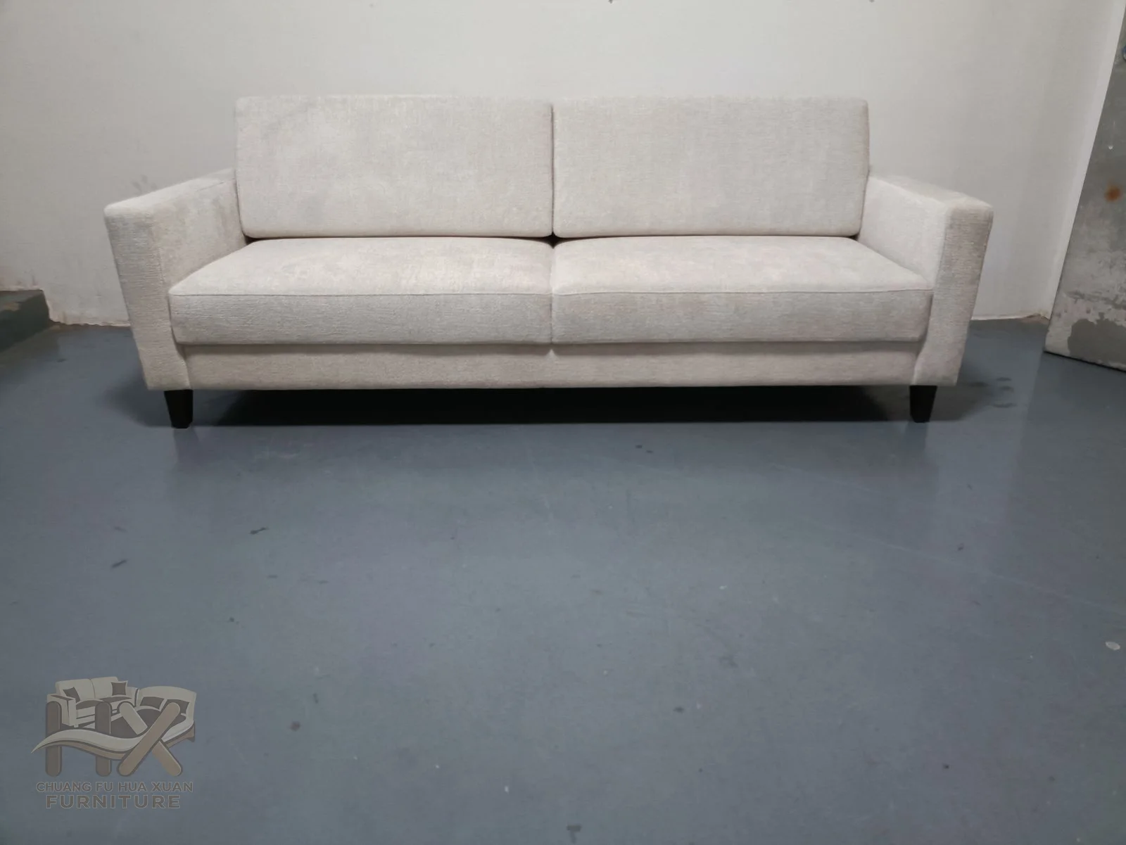 An ivory sofa has a long straight seat between low narrow arms and soft loose backs.