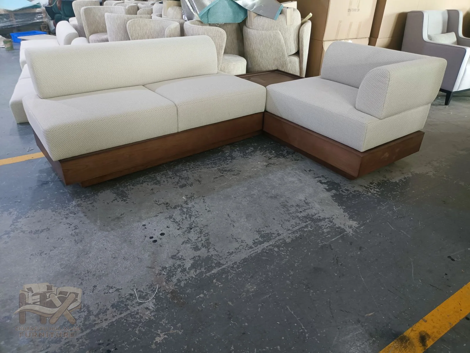 A white sectional turns around a deep corner above a visible warm wood-look plinth.