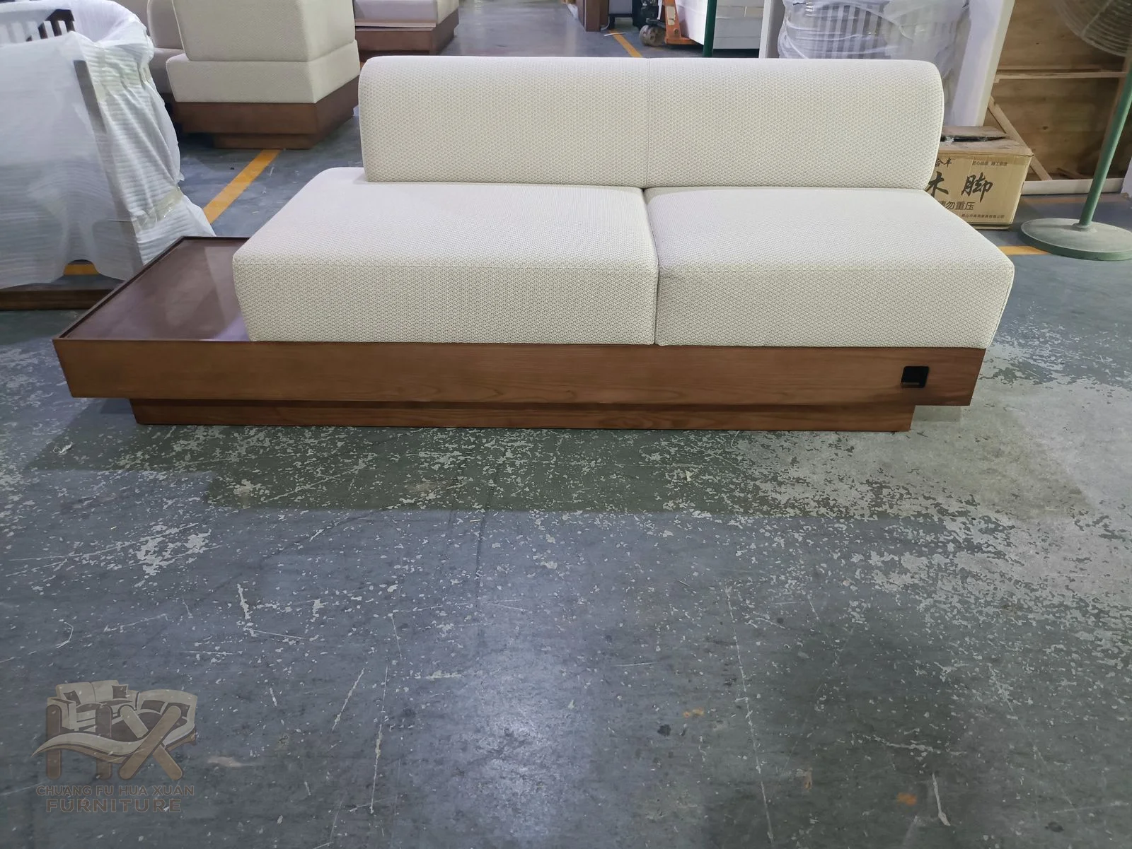 A low white sofa has broad cushions and slim arms above a continuous wood-look base.