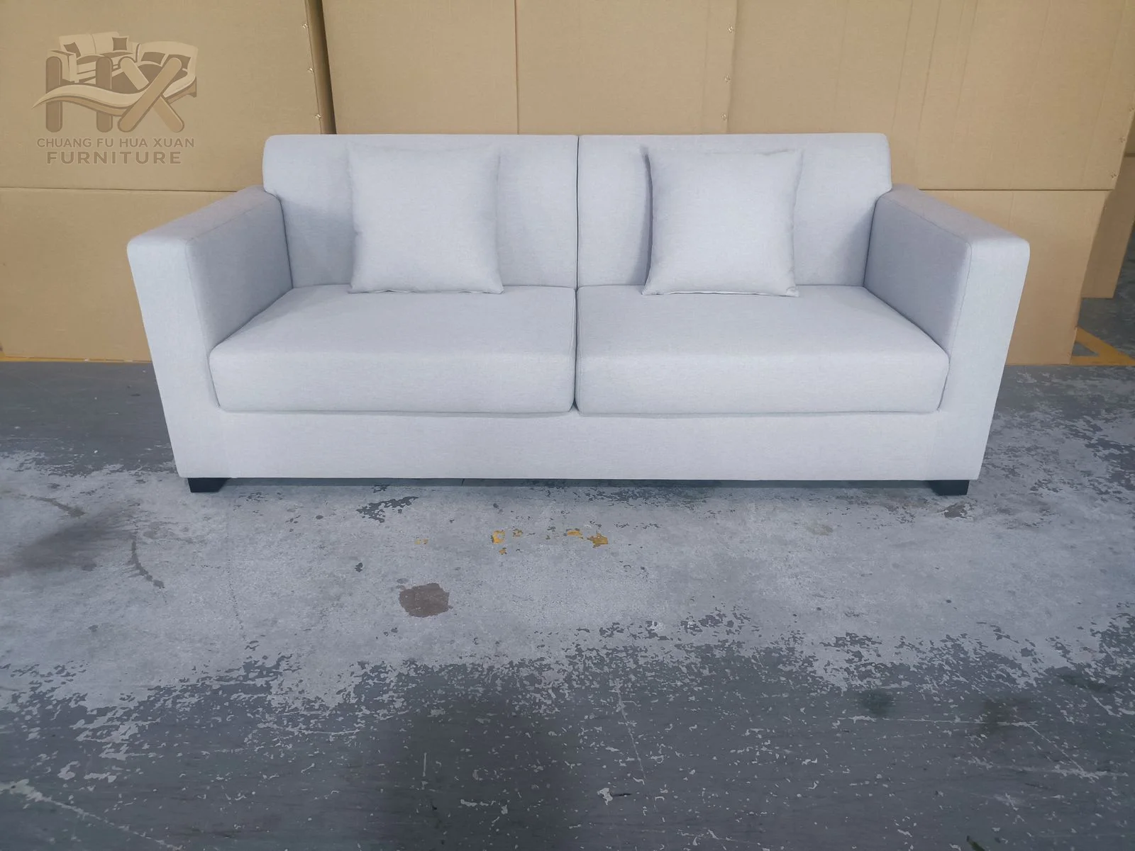 A white two-seat sofa places firm cushions between broad upright square arms.