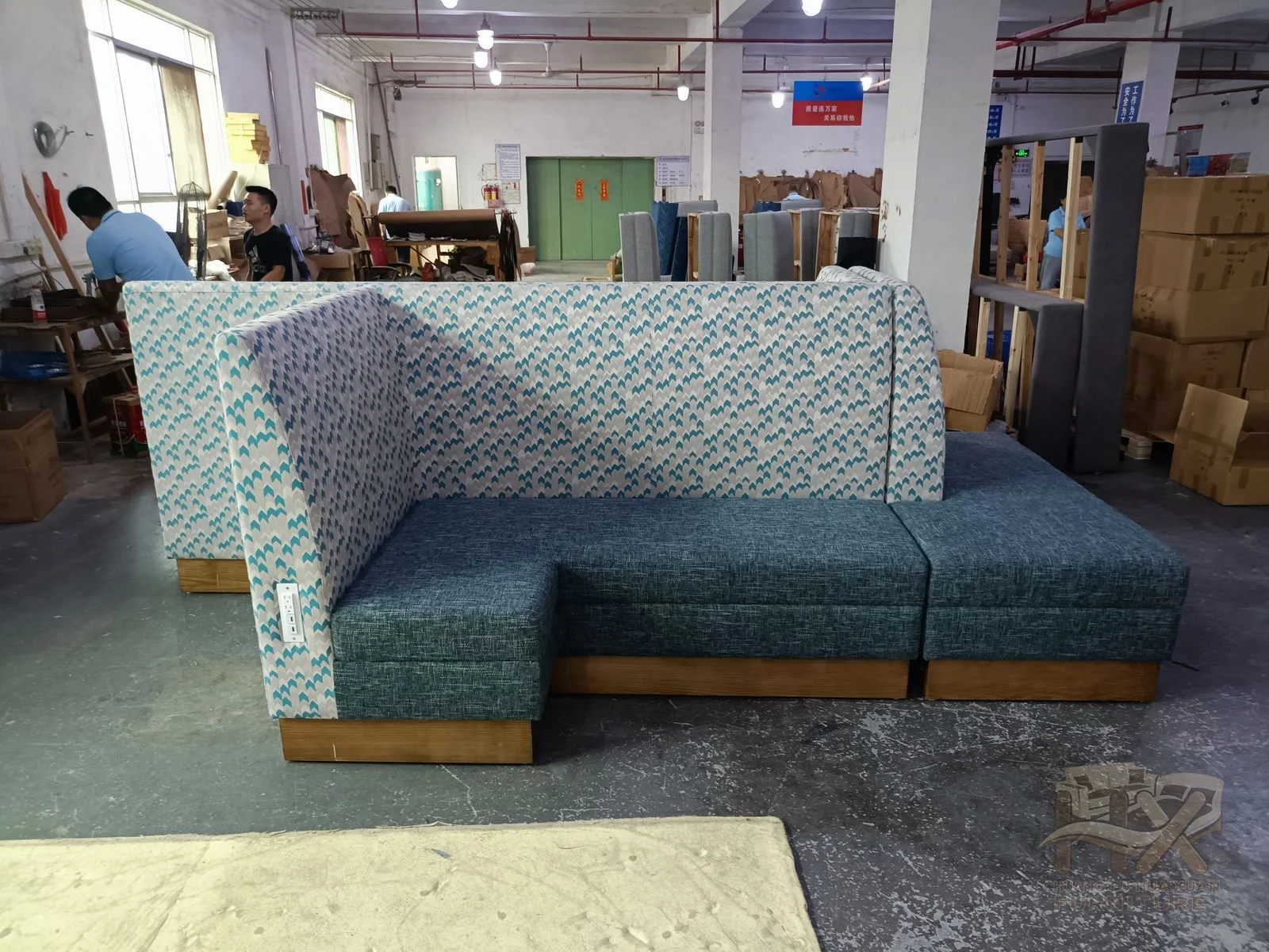 A muted blue sofa has low arms and a long cushion run with patterned loose back cushions.