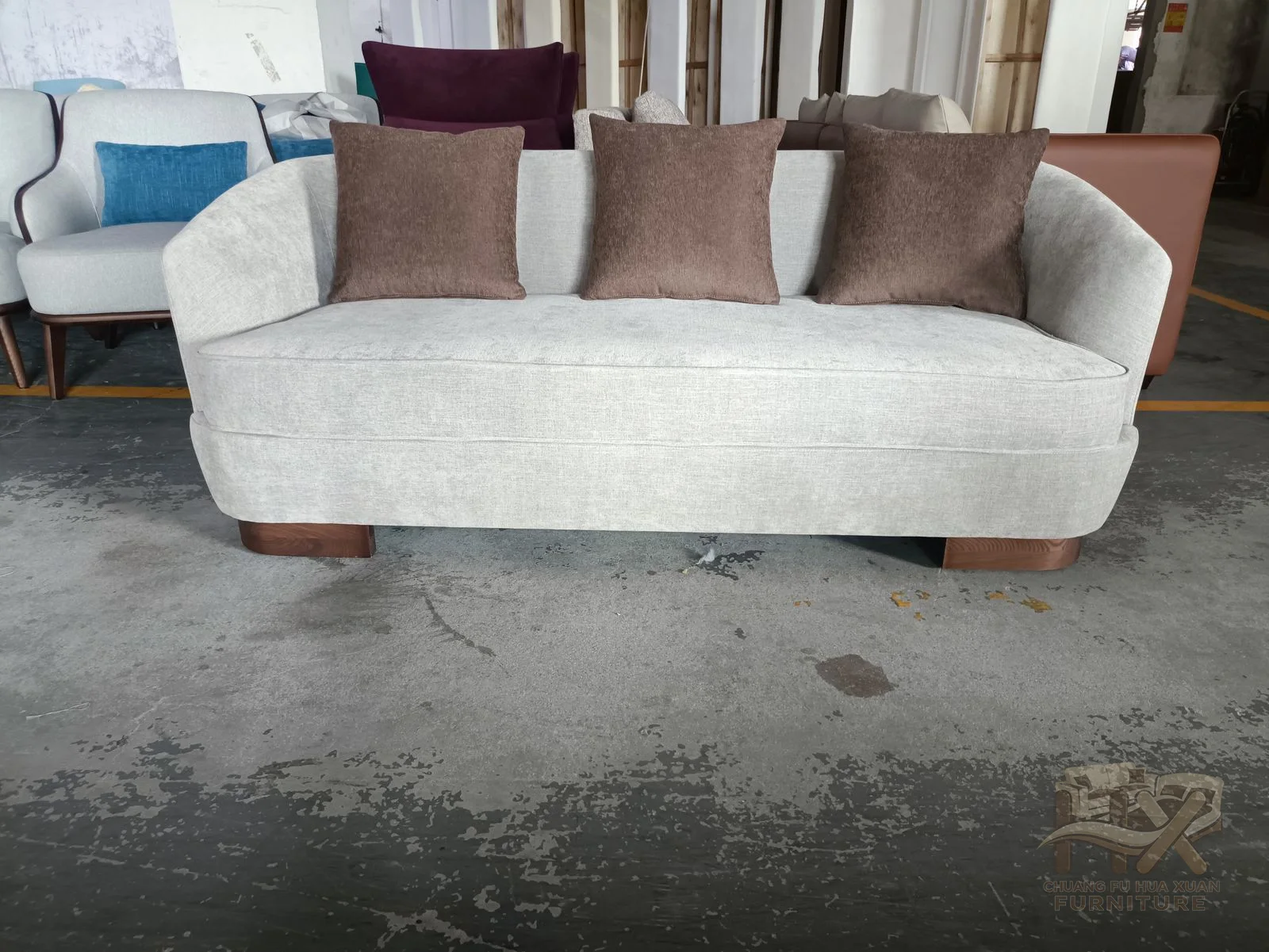 An ivory sofa uses soft rounded arms and dark brown accent cushions above a deep seat.