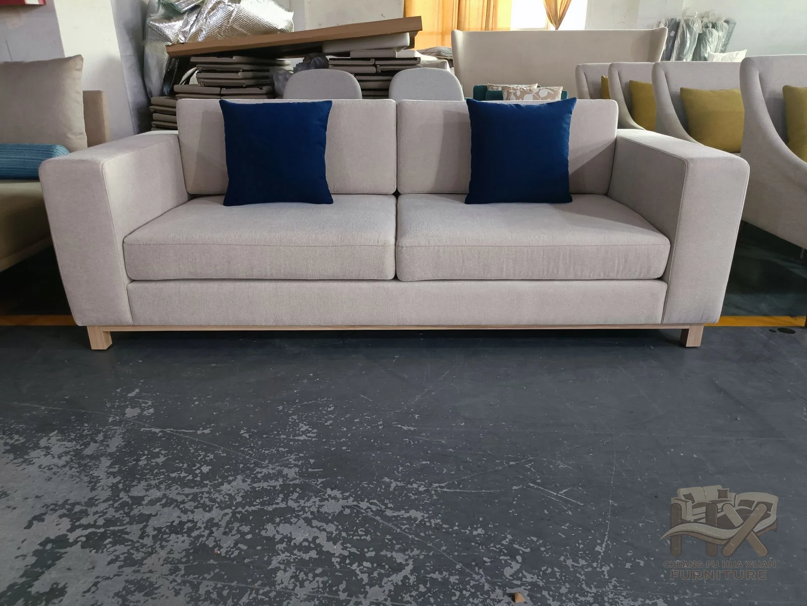 A white sofa sets blue loose cushions against a long pale seat and straight low arms.