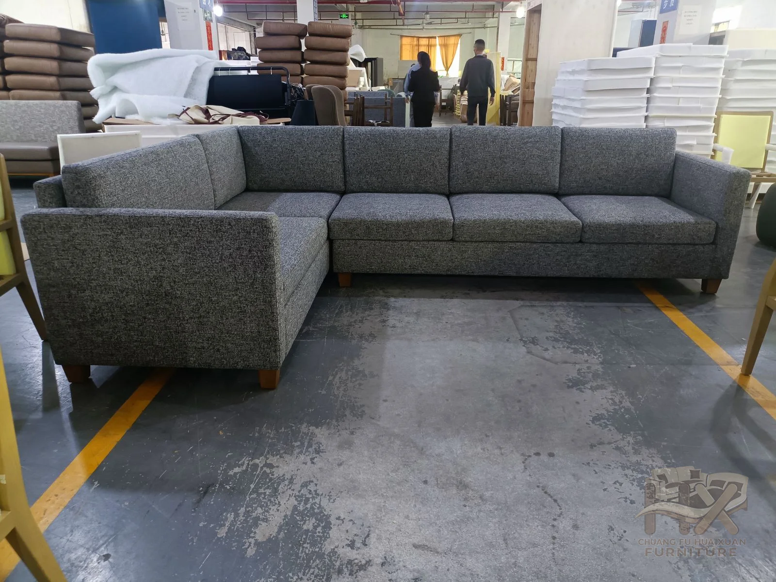 A broad charcoal sectional turns around a low deep corner with repeated cushion modules.