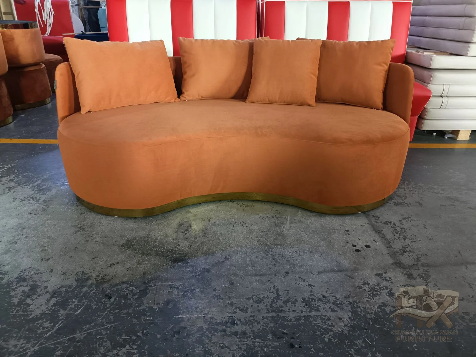 A rust sofa rounds its arms and back around a broad deep cushion run.