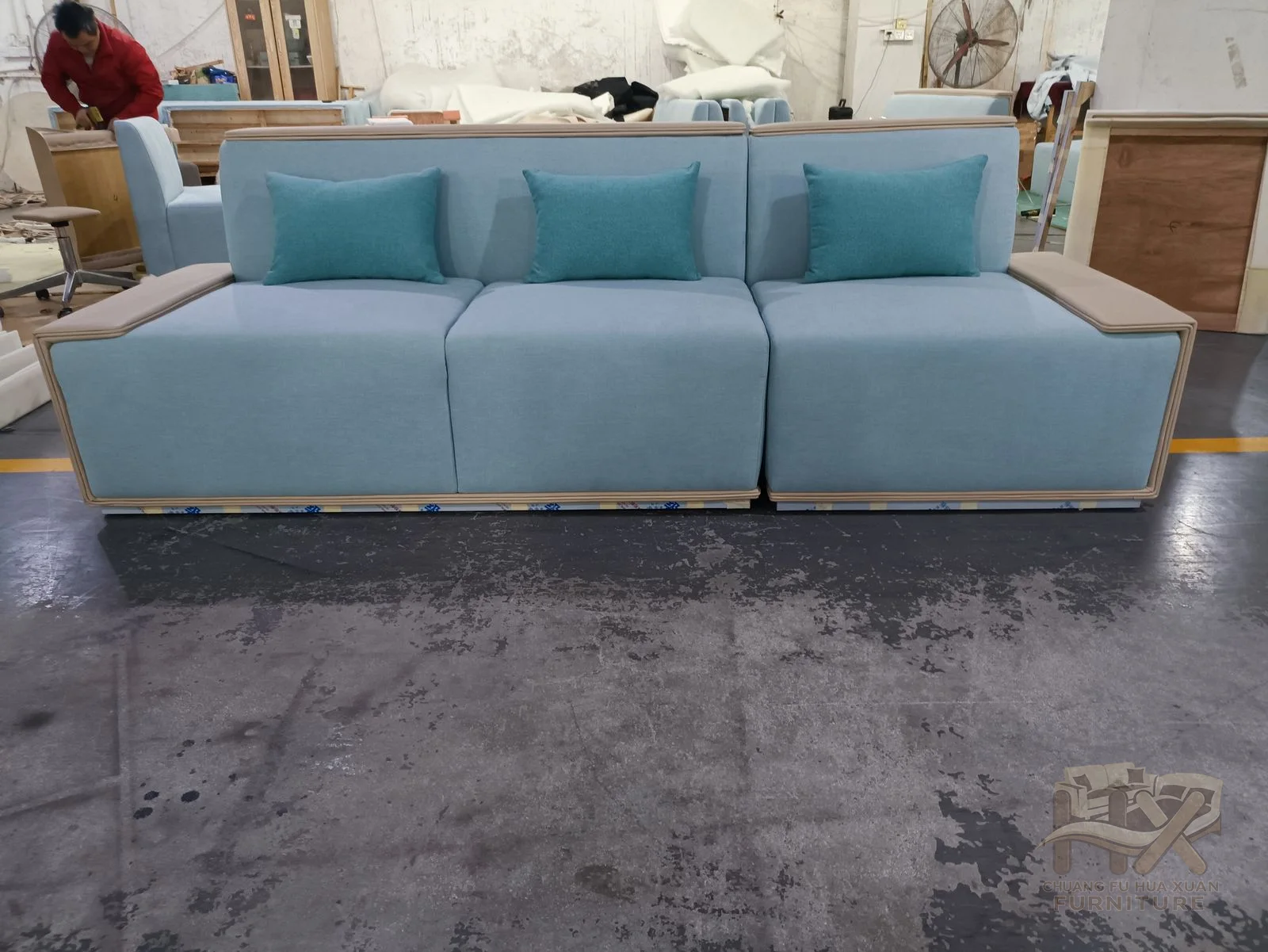 A pale blue sofa sets loose cushions within warm exposed wood-look arm ends.
