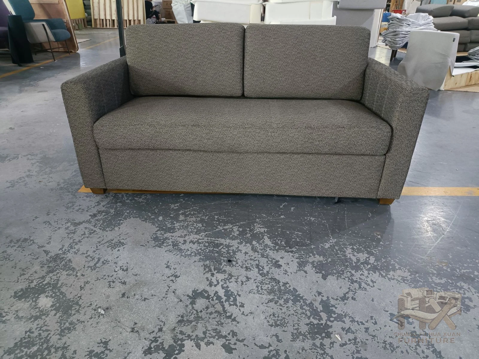 A grey two-seat sofa carries loose back cushions inside upright square arms.