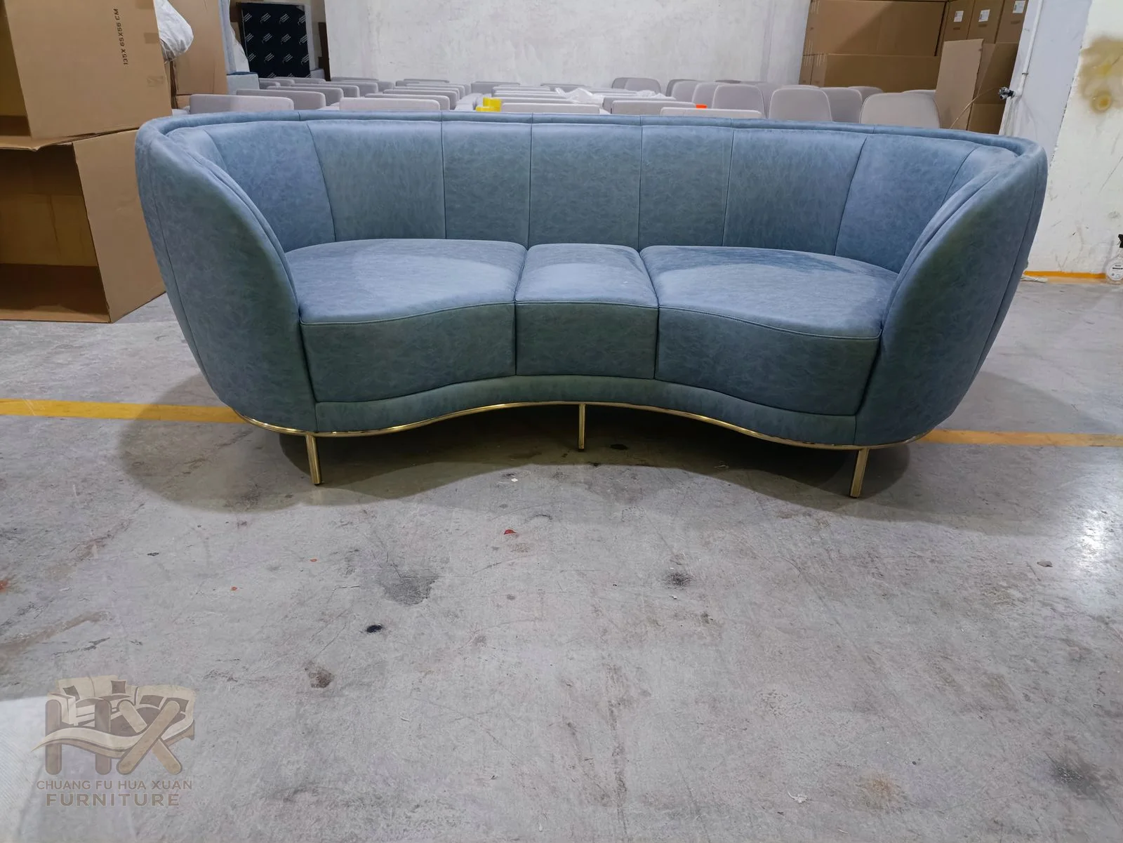 A blue two-seat sofa bends its low back around a curved continuous seat.