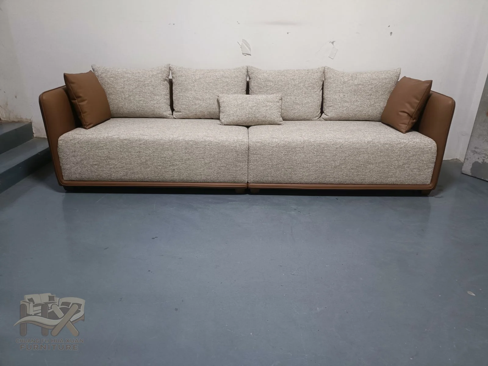Ivory cushions sit above a low seat within a tan outer arm and back frame.
