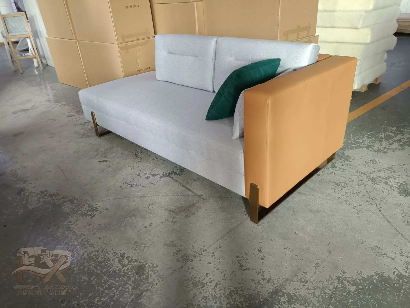 A white sofa carries loose cushions between low arms with warm wood-look outer faces.