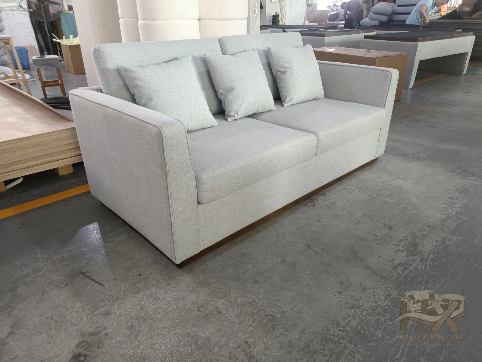 A white two-seat sofa uses narrow low arms and loose back cushions on a compact base.