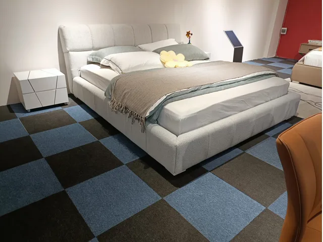 Light grey upholstered bed with paneled headboard in a showroom room setup