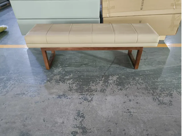 Cream upholstered bench with channel-stitched seat and timber base in the workshop