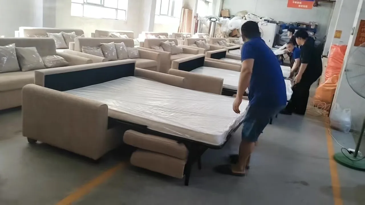 Beige folding sofa beds opened on the factory line with mattress decks and support frames visible